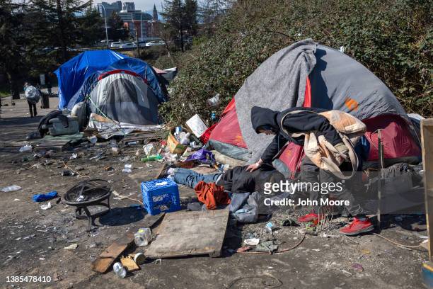 Homeless man checks on a friend who had passed out after smoking fentanyl at a homeless encampment on March 12, 2022 in Seattle, Washington. The city...