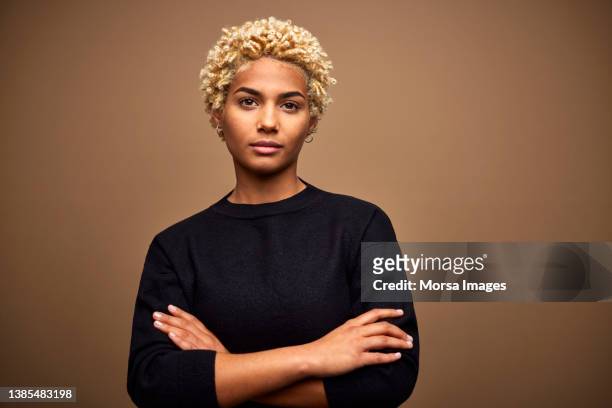 confident young female afro owner against brown background - portretfoto stockfoto's en -beelden