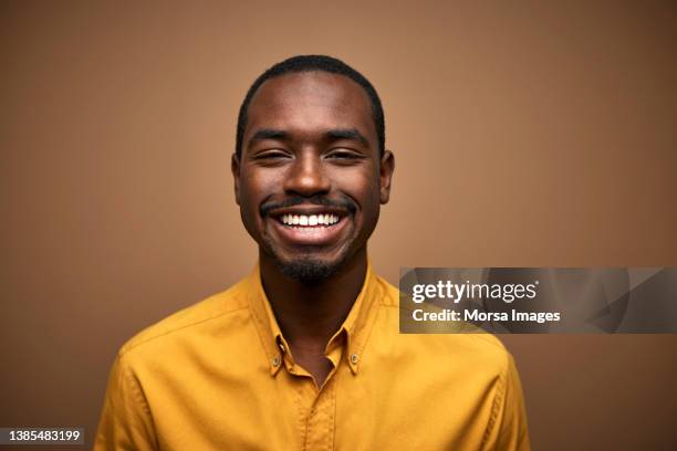 portrait of smiling african young adult man in casuals - african american man wearing shirt stock-fotos und bilder