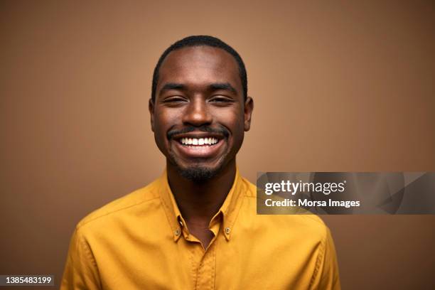 portrait of smiling african young adult man in casuals - yellow shirt fotografías e imágenes de stock