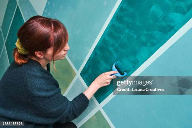 a woman paints a mural on the wall of her house. - school reform stock pictures, royalty-free photos & images