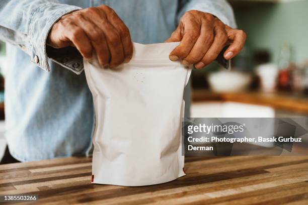 a man closing the zip lock coffee bag with degassing valve - bag stock pictures, royalty-free photos & images