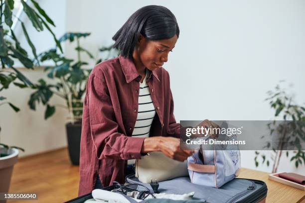young african american woman packing clothes in suitcase - garment stock pictures, royalty-free photos & images