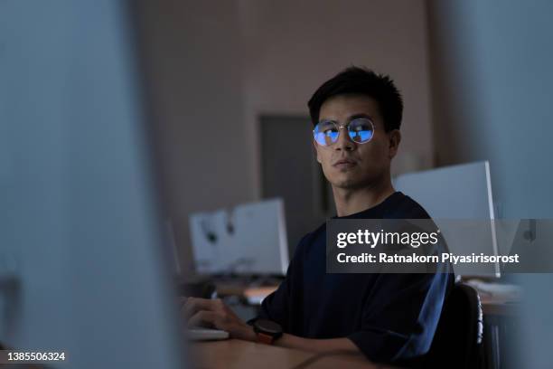 young adult asian man working late at night in their office with desktop computer. using as hard working and working late concept. programmer and hacker concept - work hard play hard stock pictures, royalty-free photos & images