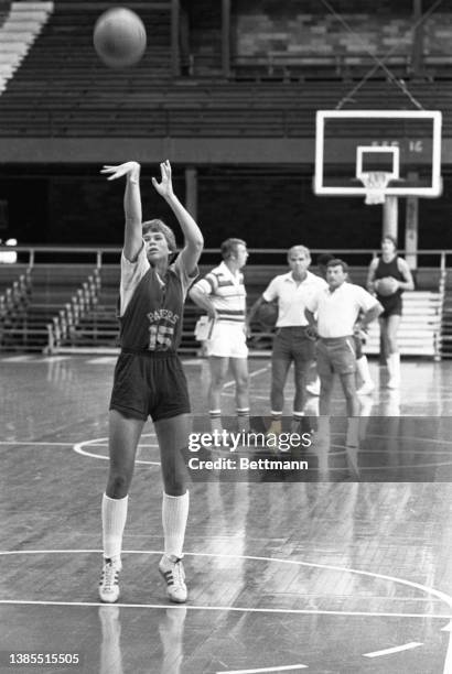 Ann Meyers, an outstanding basketball player at UCLA, shoots to the basket while Indiana Pacers coaches in the background keep an eye on her. She and...