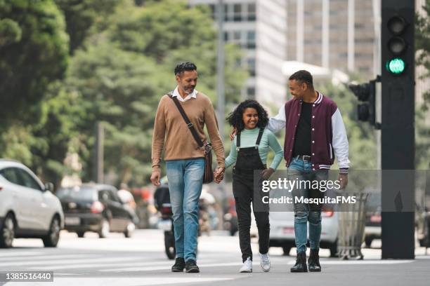 gay couple walking hand in hand with adopted daughter - crossing street stock pictures, royalty-free photos & images