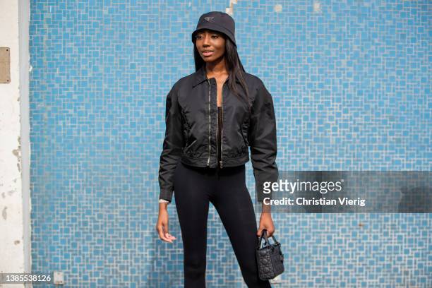 Jasmin Jaegers is seen wearing black Prada hat, bomber jacket, leggings, Dior bag, knee high boots during Berlin Fashion Week on March 15, 2022 in...