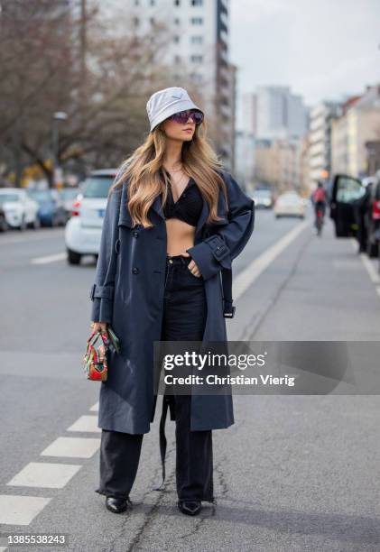 Jessy Hartel wearing lavender Prada hat, navy double breasted trench coat, cropped top, dark denim mom jeans seen during Berlin Fashion Week on March...