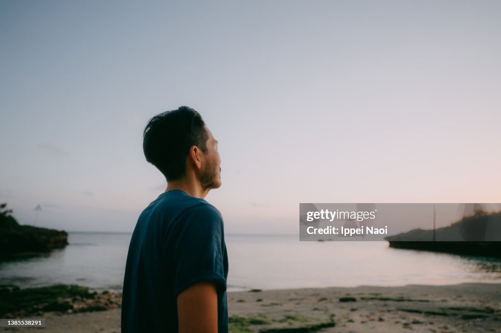 Man contemplating on beach at dusk