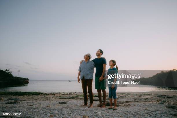 grandfather, father and granddaughter on beach at dusk - multi generation family thinking stock pictures, royalty-free photos & images