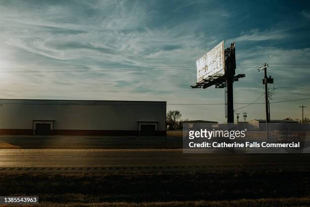 building and a billboard beside an american highway at sunset - interstate highway usa stock-fotos und bilder
