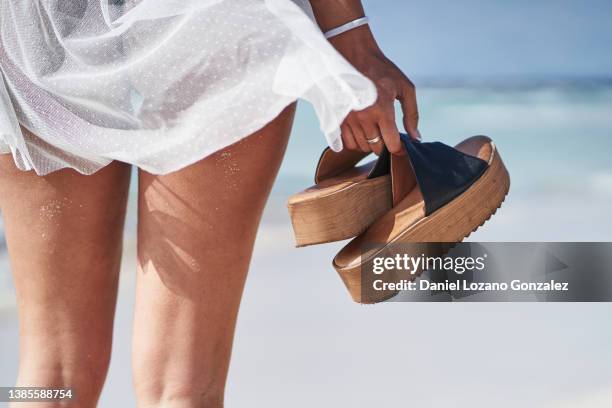 woman with sandals in hand on sandy seashore - putten stock pictures, royalty-free photos & images