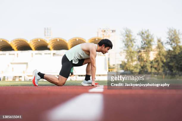 young man track athlete at starting block - course sur piste hommes photos et images de collection