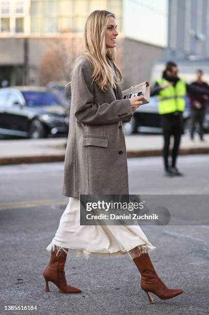 Guest is seen wearing a gray coat and cream dress and brown boots outside the Alexander McQueen AW22 show on March 15, 2022 in the borough of...