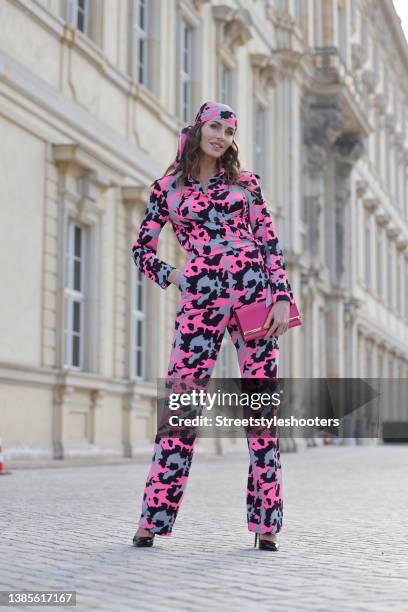 Influencer Anna Verkhorubova wearing a pink, grey and black camouflage print bandana and jumpsuit by Natascha Gruen, a pink clutch by Victoria Secret...