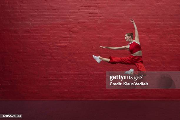 dancer jumping against red wall - modern dancing photos stock pictures, royalty-free photos & images
