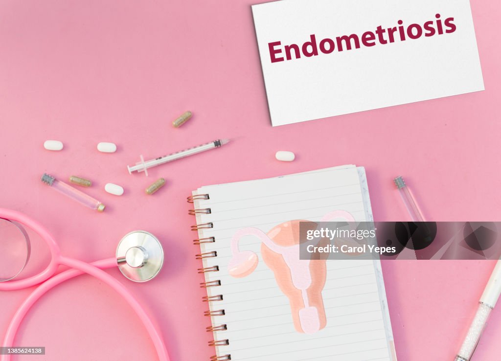 Medical desk with notepad showing endometriosis message.Pills, uterus.