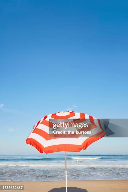 striped parasol on the beach against blue sky - parasol stockfoto's en -beelden