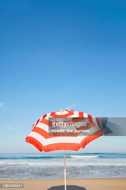 striped parasol on the beach against blue sky - sunscreen imagens e fotografias de stock