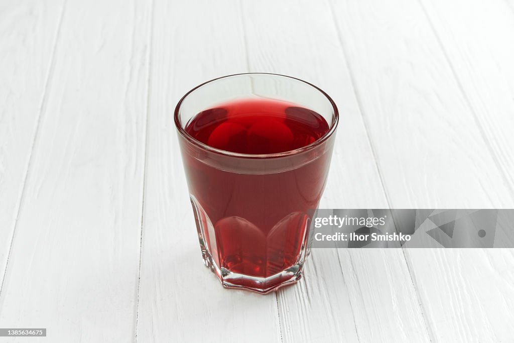 Berry compote in a clear glass on a white wooden background