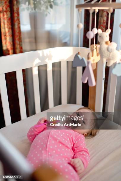 cute happy baby girl in pink bodysuit with toy rattle, having fun indoors in a sunny morning - happy mobile stockfoto's en -beelden