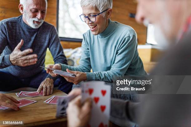 gruppe von glücklichen senioren spielen karten zu hause. - card game mature people stock-fotos und bilder