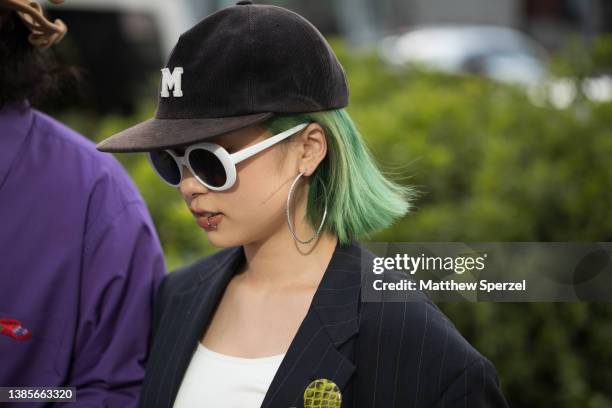 Guests are seen wearing purple collared shirt, orange mesh shirt, brown bag, navy pants with scarf knee accessory, black shoes and brown felt hat;...