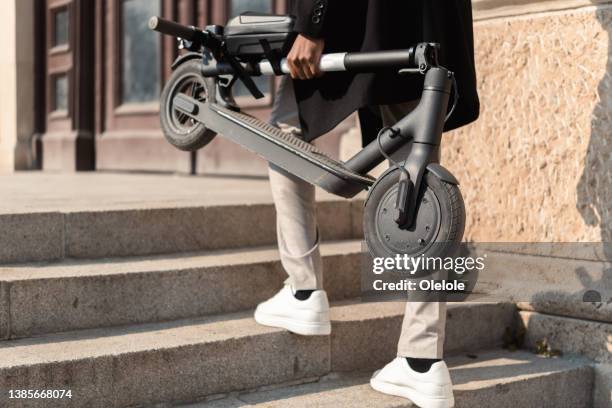 unrecognizable young man carrying a push scooter - electric push scooter stock pictures, royalty-free photos & images