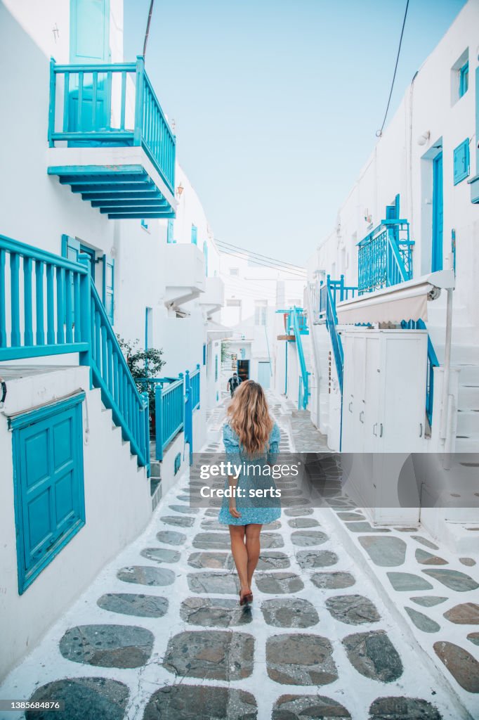 Young tourist woman walks through the streets of Mykonos Island, Cyclades, Greece