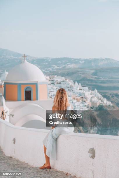 young woman enjoys travelling and looking at view in santorini, greece - greece stock pictures, royalty-free photos & images