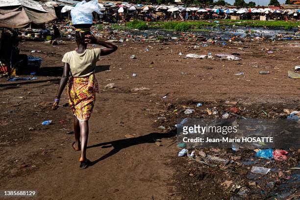 Déchets plastiques dans la rue et femme de dos le 27 octobre 2021 à Conakry en Guinée.