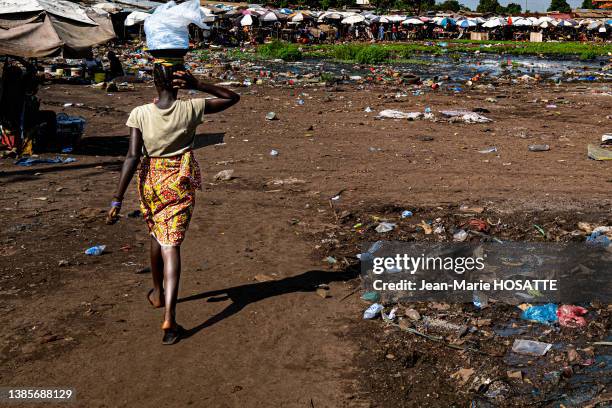 Déchets plastiques dans la rue et femme de dos le 27 octobre 2021 à Conakry en Guinée.