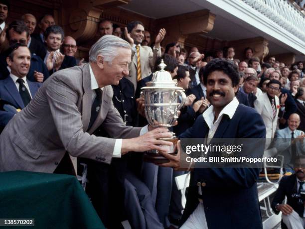 The captain of India, Kapil Dev, receives the Prudential World Cup Trophy from the Chairman of Prudential Assurance, Lord Carr of Hadley, after...