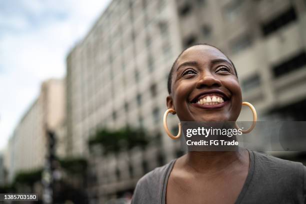 contemplative mid adult woman in the street - dankbaarheid stockfoto's en -beelden