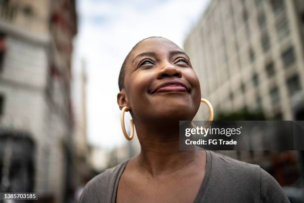 contemplative mid adult woman in the street - inspiratie stockfoto's en -beelden