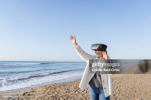 young woman using virtual reality headset on beach .female playing video games interacting and gesturing with virtual reality simulator - virtual reality point of view stock pictures, royalty-free photos & images