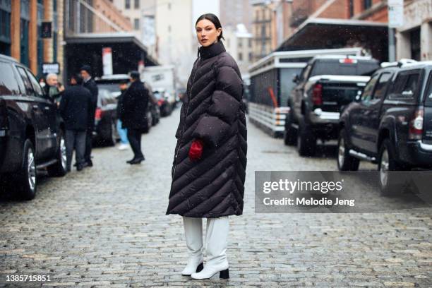 American model Jacquelyn Jablonski wears a long black puffer coat, red leather gloves, and knee-high white leather boots after the Khaite show during...