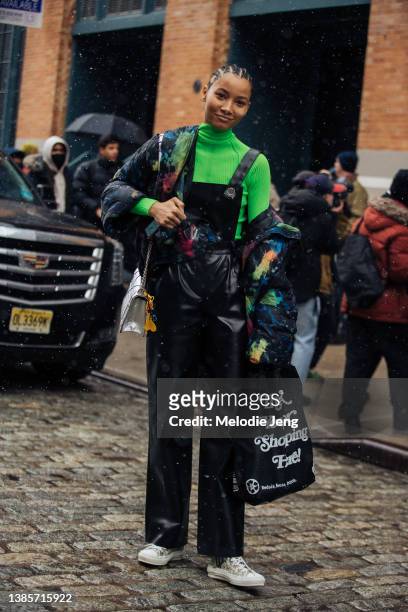 Dominican model Lineisy Montero wears a green top, black tie-dye paint jacket off her shoulder, black leather overalls, white Dior logo sneakers, and...