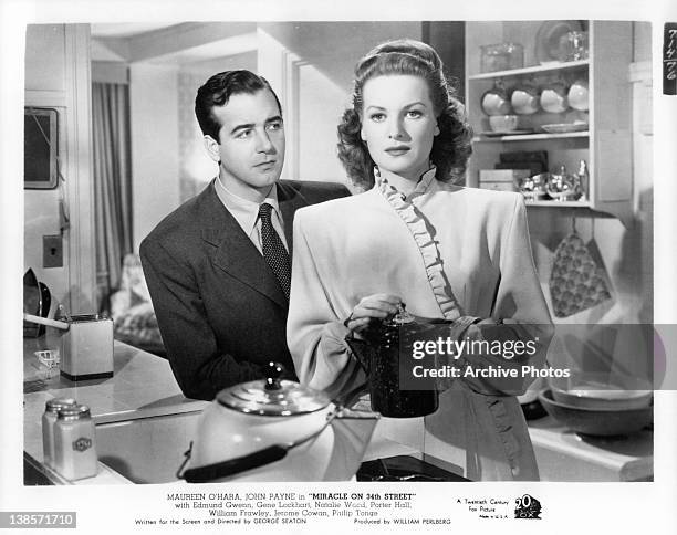 John Payne stands in back of Maureen O'Hara as she holds a coffee pot in a scene from the film 'Miracle On 34th Street', 1947.