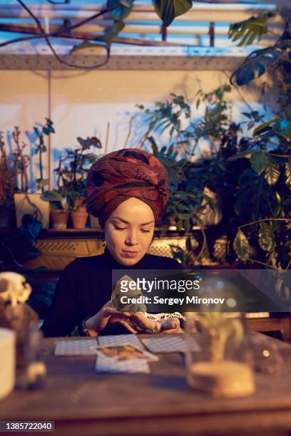fortune teller with cards and skull at table - tarot cards stock-fotos und bilder