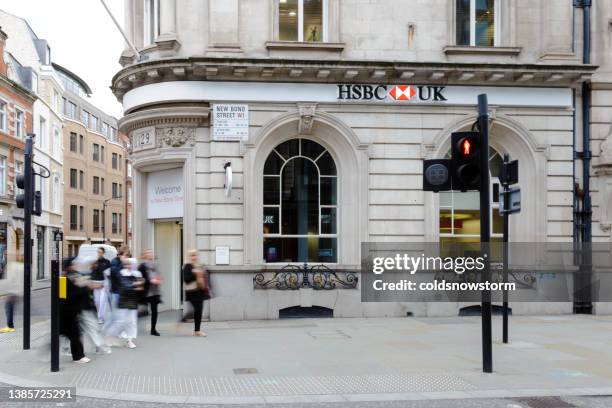 blurred motion of people walking past hsbc bank on city street - high street bank stock pictures, royalty-free photos & images