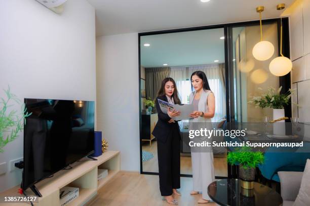 real estate female agent showing the brochure to female customer at - investment brochures foto e immagini stock