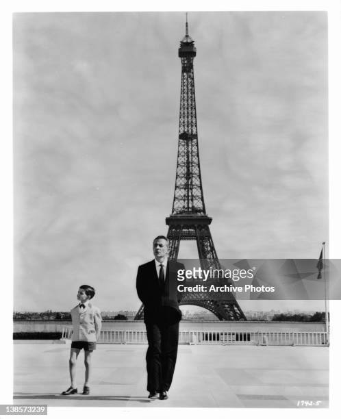 Martin Stephens as Rossano Brazzi's son, strike a similar pose before the Eiffel Tower in a scene from the film 'Count Your Blessings', 1958.