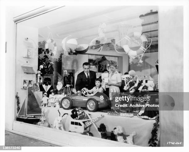 Martin Stephens sees the toy car of his dreams, as he shops with Rossano Brazzi in a scene from the film 'Count Your Blessings', 1958.