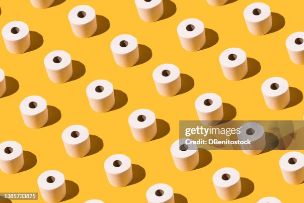 pattern of white toilet paper rolls on yellow background. concept of going to the bathroom, cleaning and pooping and peeing. - diarrhö stock-fotos und bilder