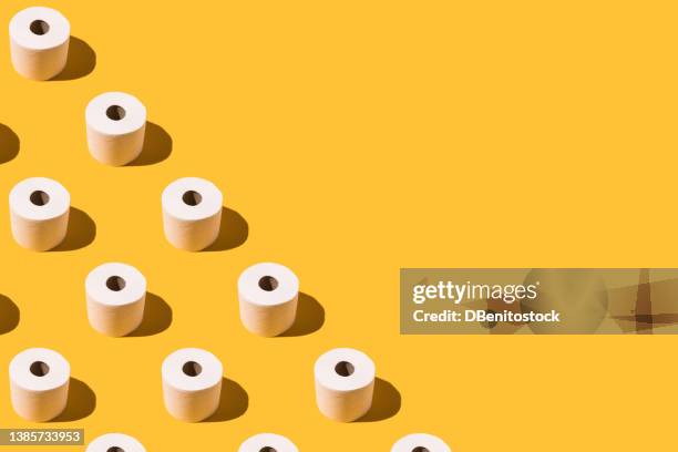 pattern of white toilet paper rolls, on the left side, on yellow background. concept of going to the bathroom, cleaning and pooping and peeing. - men taking a dump stockfoto's en -beelden