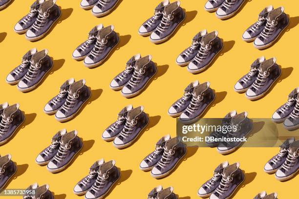 old style worn blue basketball shoe pattern on yellow background. fashion, modern, retro and casual footwear concept. - paio foto e immagini stock