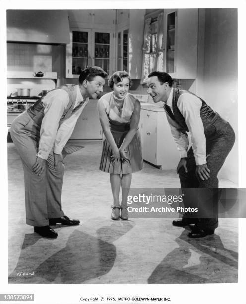 Donald O'Connor, Debbie Reynolds, and Gene Kelly hunching over together in a scene from the film 'Singin' In The Rain', 1952.