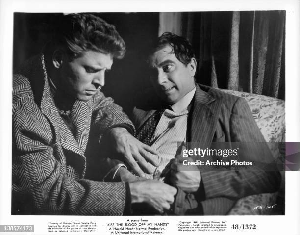 Burt Lancaster looks Robert Newton's wound in a scene from the film 'Kiss The Blood Off My Hands', 1948.