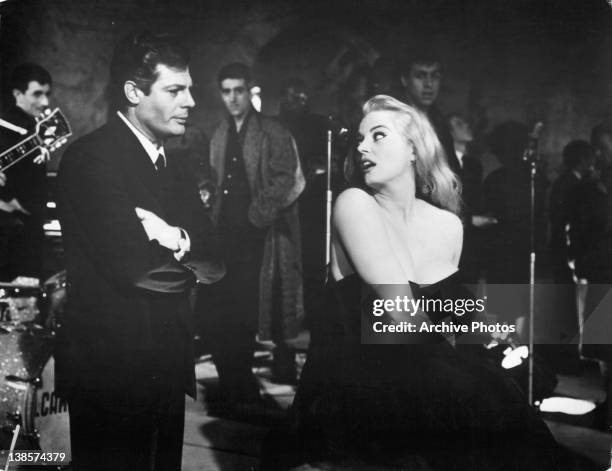 Marcello Mastroianni with his arms folded looking at Anita Ekberg in a scene from the film 'La Dolce Vita', 1960.